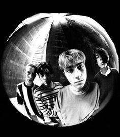 three young men are standing in front of a round mirror with one man looking at the camera