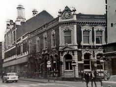 an old black and white photo of people walking on the street in front of buildings