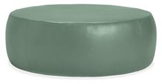 a green leather ottoman sitting on top of a white floor