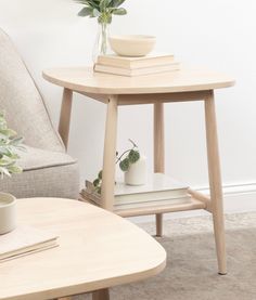 a small table with some books and a vase on it next to a couch in a living room