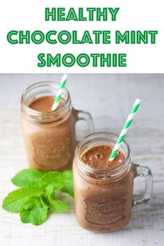 two mason jars filled with chocolate mint smoothie on top of a white table next to green leaves