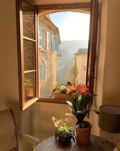 an open window with flowers on the table in front of it