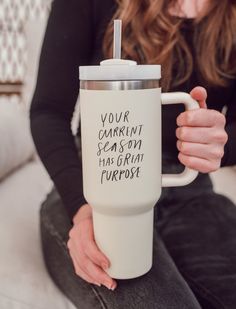 a woman sitting on a couch holding a coffee cup with writing on the bottom and inside