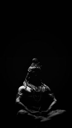 black and white photograph of a woman sitting in the dark with her hands behind her back