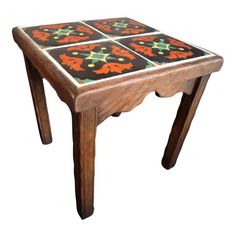 a small wooden table with four different colored tiles on the top and bottom, sitting in front of a white background