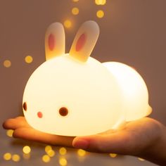 a hand holding a small light with two bunny ears on it's face and eyes