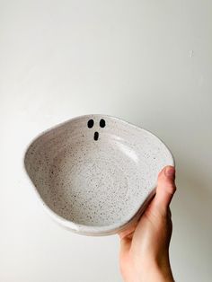 a hand holding a white bowl with black dots