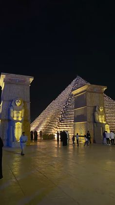 the pyramids are lit up at night with people walking around