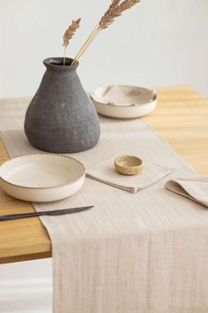 the table is set with two plates and a vase on it, along with silverware