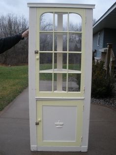 a yellow and white cabinet sitting on the side of a road next to a house