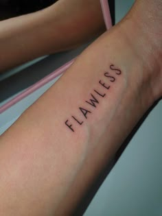 a woman's arm with the word flawless tattooed on her left forearm