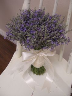 a bouquet of purple flowers sitting on top of a white chair