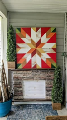 a painting on the wall above a fireplace in a porch with potted plants and a rug