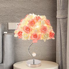 a lamp that has flowers on it sitting on a table next to a gray chair