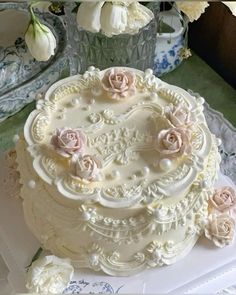 a wedding cake with white frosting and pink roses