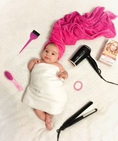 a baby laying on its back next to hairdryers, combs and other items