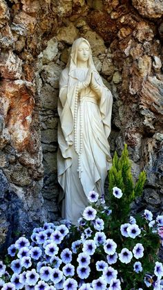 the statue is surrounded by flowers and rocks