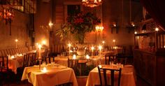 a dining room filled with lots of tables covered in white tablecloths and lit candles