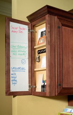 a kitchen cabinet with a sign on the wall above it and a bowl of fruit in front of it