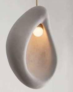 a white light hanging from a ceiling with a droplet shaped like a tear on it's side