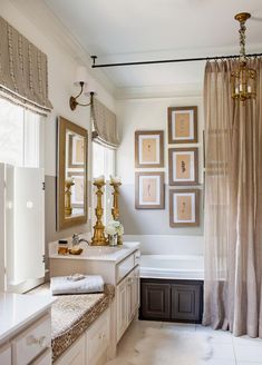 a bath room with a tub a sink and some pictures on the wall above it