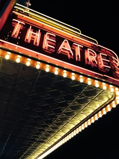 the theatre sign lit up at night with bright lights on it's sides and bottom