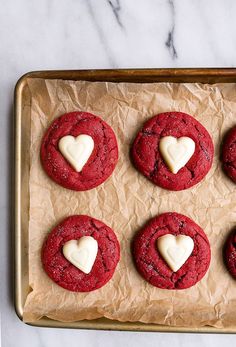 red velvet cookies with white heart decorations on parchment paper