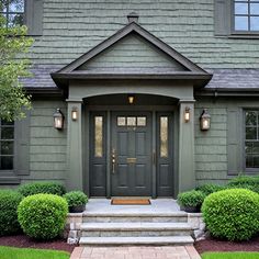 the front door of a house with steps leading up to it and bushes in front