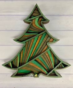 a green wooden christmas tree hanging on a white wood planks wall in the shape of a fir tree