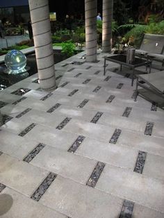 an outdoor patio area with chairs, tables and water feature in the background at night