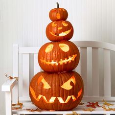 three carved pumpkins stacked on top of each other in front of a white chair