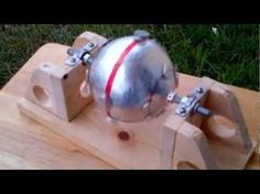 a metal ball sitting on top of a wooden table next to a piece of wood