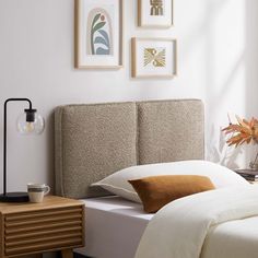 a bed with two framed pictures on the wall above it and a lamp next to it