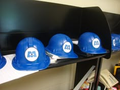 five blue hard hats sitting on top of a shelf