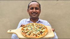 a man holding a pizza on a wooden board