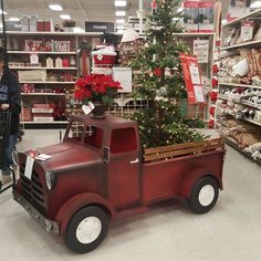 an old red truck with a christmas tree in the bed is on display at a store