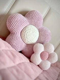 a crocheted teddy bear sitting on top of a bed next to a pink pillow