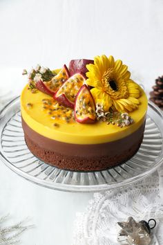 there is a cake with fruit and flowers on the top, sitting on a glass platter