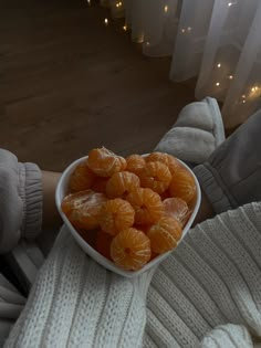 a person holding a bowl full of peeled oranges