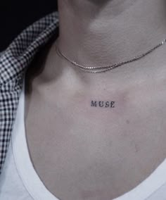 a woman's chest with the word muse tattooed on her left side ribcage