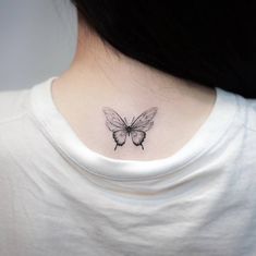 a woman's neck with a small butterfly tattoo on the left side of her neck