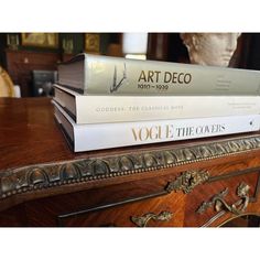 three books stacked on top of each other in front of a table with a statue