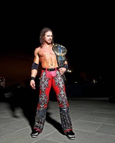 a man standing on top of a tile floor holding a wrestling ring belt in his hand