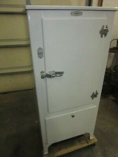 an old white refrigerator sitting in a garage