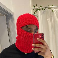 a person wearing a red knitted mask and holding a cell phone in front of their face