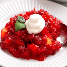 a white plate topped with cranberry sauce covered in whipped cream and garnish