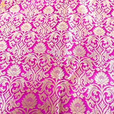 a pink and gold brocaded fabric with white flowers on the bottom half of it