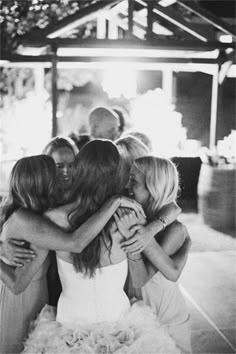 a group of women hugging each other at a wedding