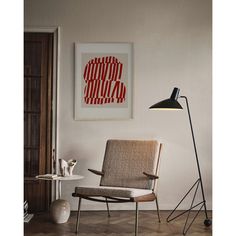 a living room with a chair, lamp and pictures on the wall in front of it