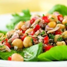 a white plate topped with lettuce covered in chickpeas and garbanzo